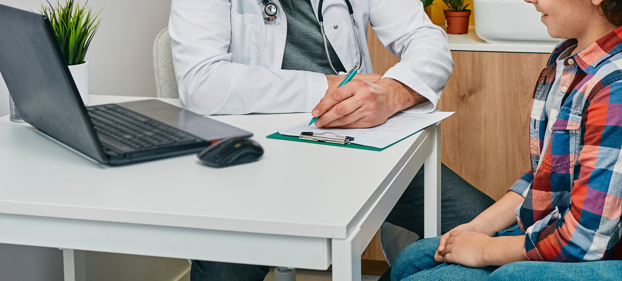 Male clinician writing down notes whilst sat with child patient