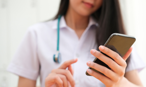 Female clinician using smartphone with stethoscope round neck