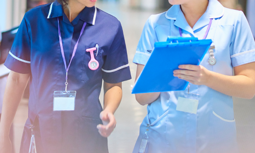 Two clinicians discussing information on a clipboard