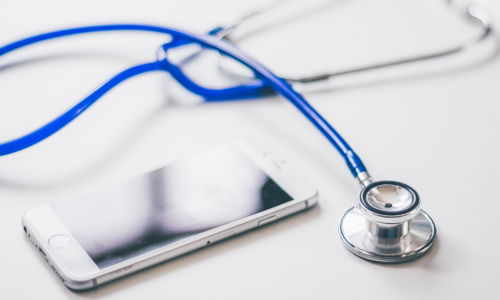 A smartphone and a stethoscope laying on a white background