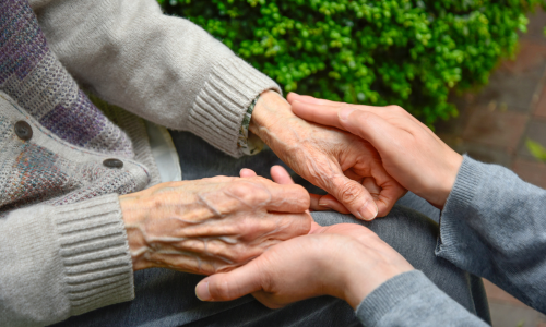 Clinician holding the hands of frailty patient