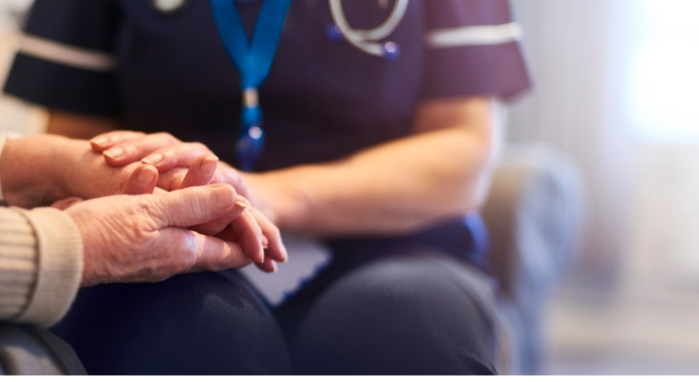 Female clinician holding the hand of elderly patient
