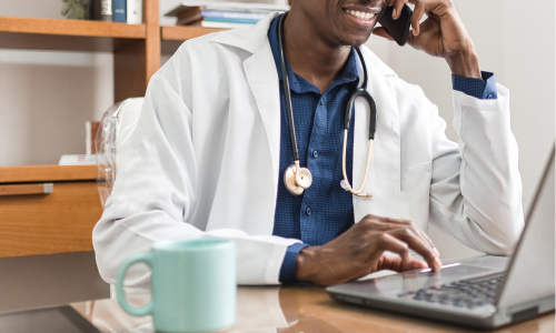 Male Doctor On The Phone, looking at his laptop